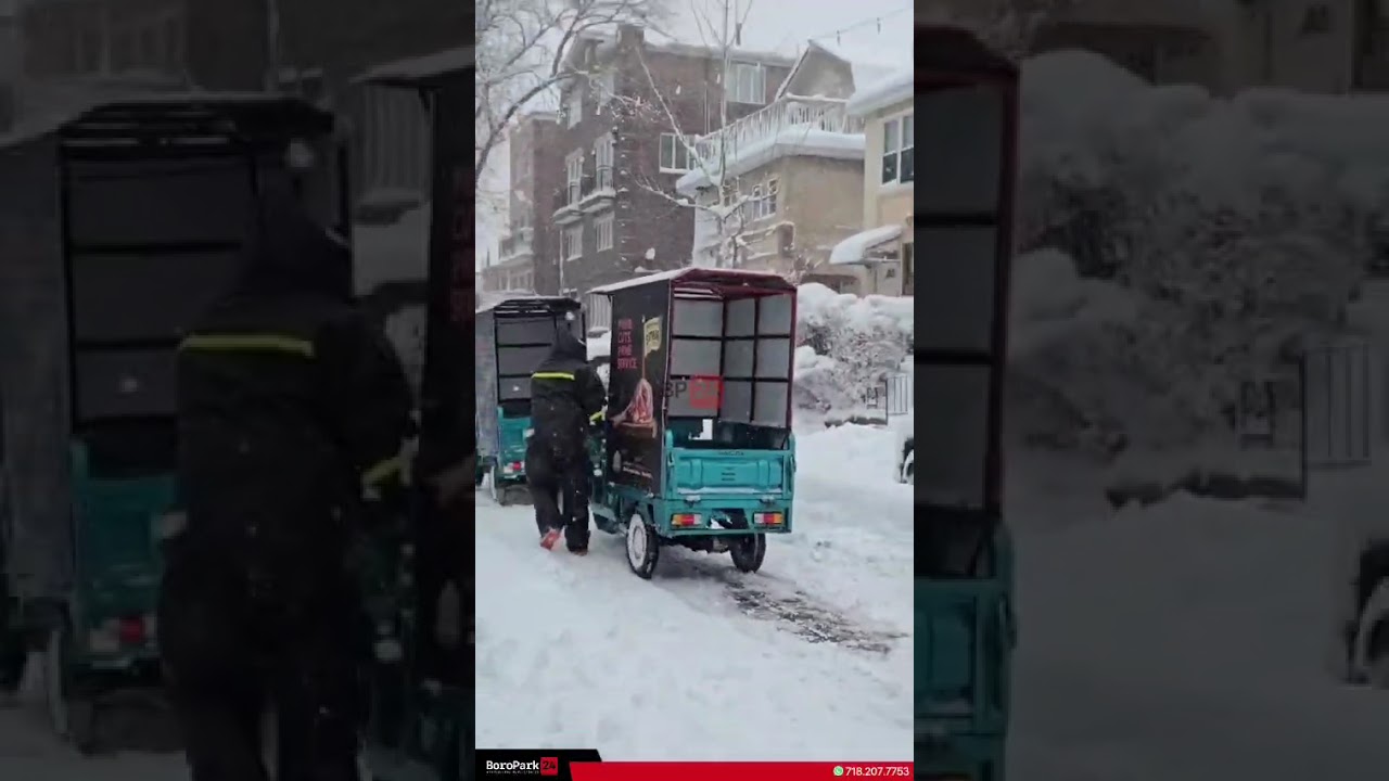 Delivery carts pushed through the snow, with one pulling another free to keep deliveries going