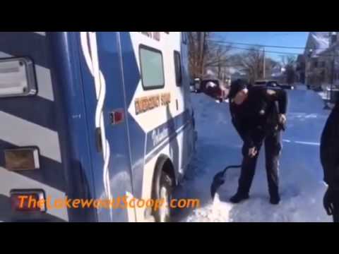 Police officer digging out ambulance stuck in snow