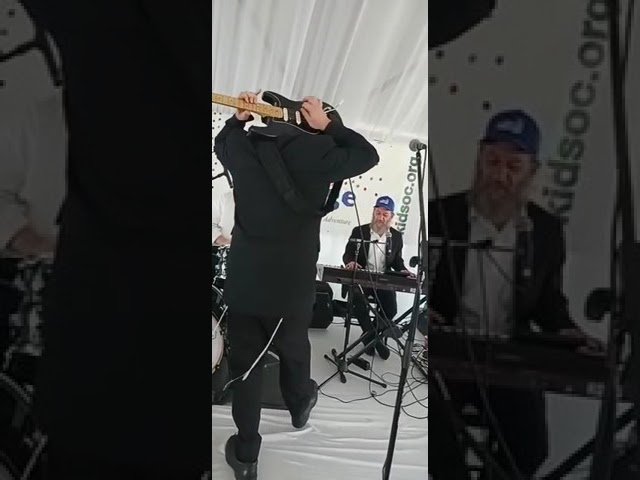 Joey Newcomb playing Guitar behind his head at a Kids of Courage event.